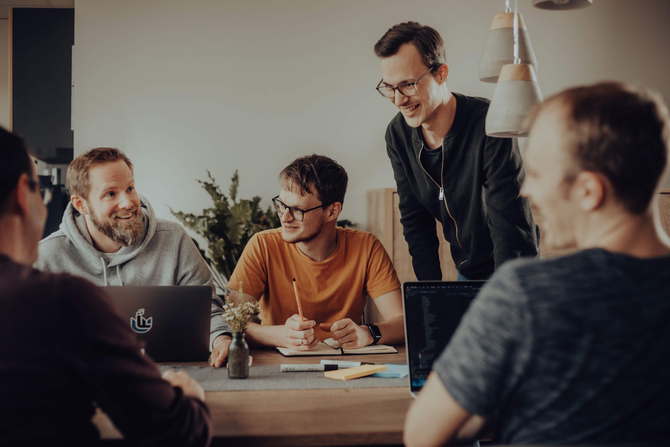 Team aus Softwareentwicklerinnen und Softwareentwicklern in einem Gespräch an einem Tisch